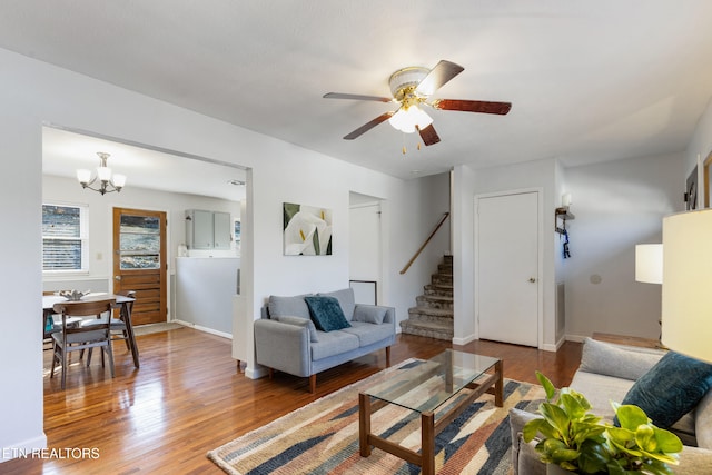 living room with hardwood / wood-style flooring and ceiling fan with notable chandelier