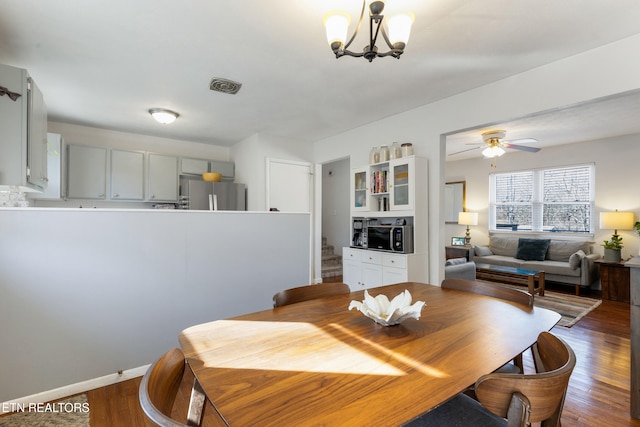 dining area with ceiling fan with notable chandelier and dark hardwood / wood-style floors