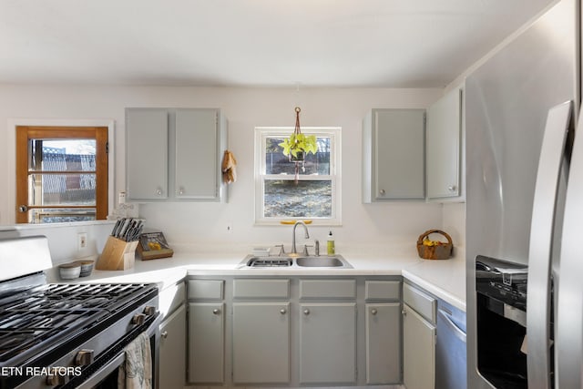 kitchen with gray cabinetry, sink, and stainless steel appliances