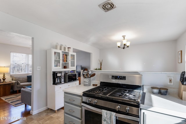 kitchen with gas range, an inviting chandelier, and white cabinets