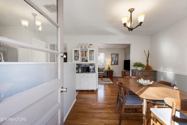 dining area with dark hardwood / wood-style floors and a chandelier