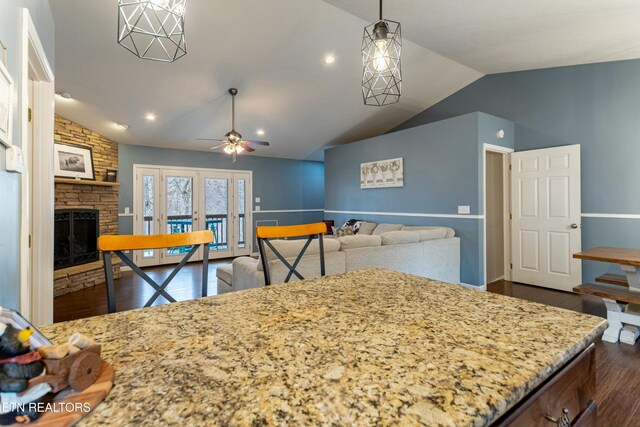 kitchen featuring vaulted ceiling, dark hardwood / wood-style floors, a fireplace, ceiling fan, and french doors