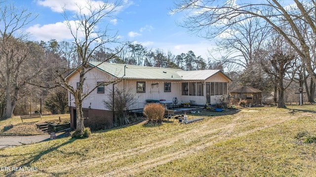 rear view of property featuring a sunroom and a yard