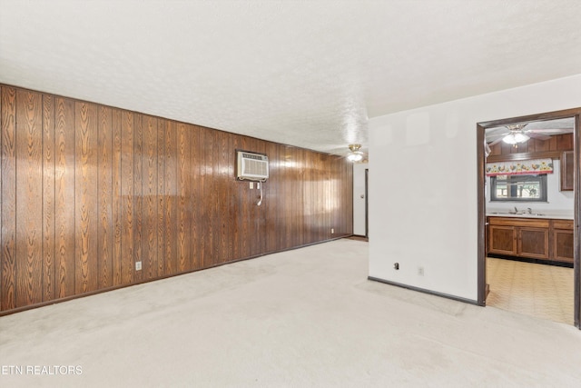 spare room with sink, a textured ceiling, wooden walls, and ceiling fan