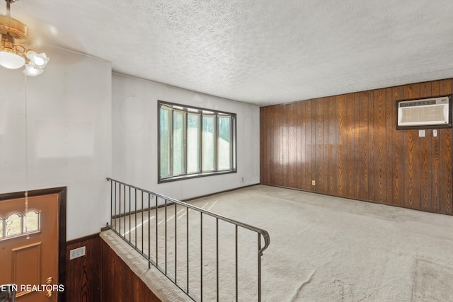 interior space with a wall mounted air conditioner, a textured ceiling, and wood walls