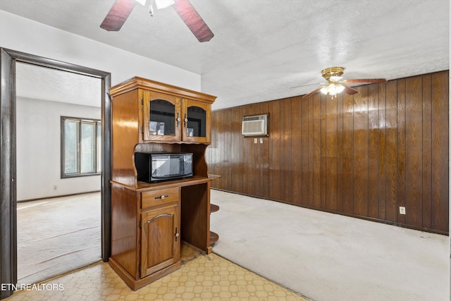 kitchen featuring ceiling fan, light carpet, a wall mounted air conditioner, and wooden walls