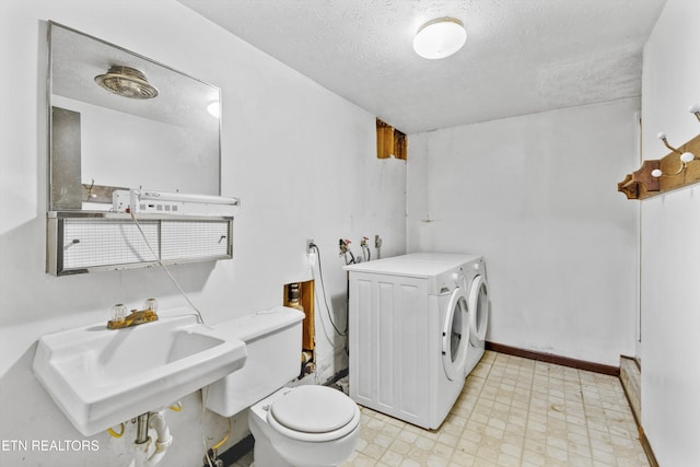 laundry area with sink, washer and dryer, and a textured ceiling