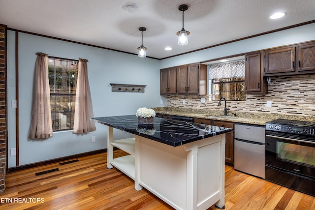 kitchen featuring sink, crown molding, hanging light fixtures, light wood-type flooring, and black range