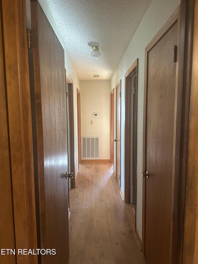 hallway featuring a textured ceiling and light wood-type flooring