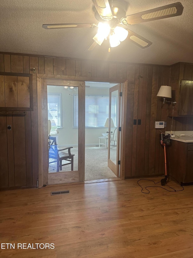 entryway with hardwood / wood-style flooring, wooden walls, and a textured ceiling