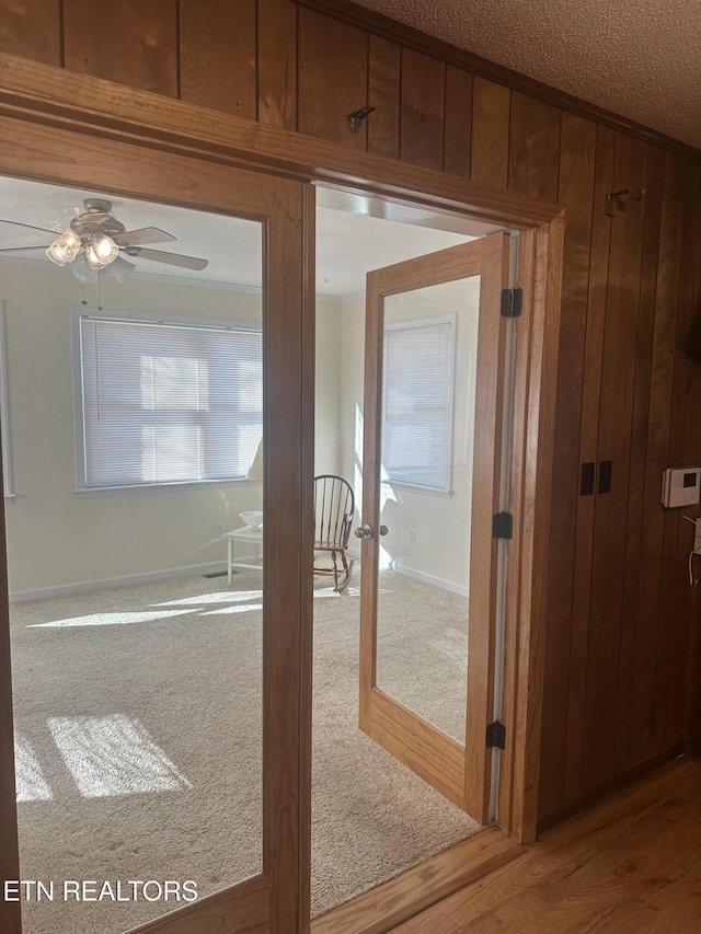 corridor featuring carpet flooring, wood walls, and french doors