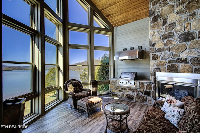 sunroom featuring a water view, wood ceiling, a fireplace, and lofted ceiling