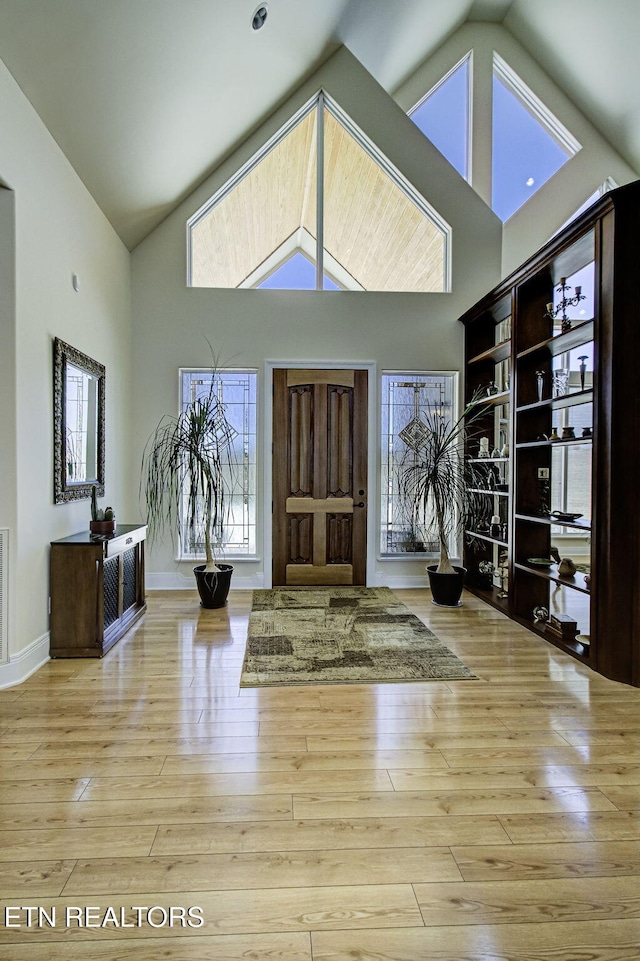 entryway with baseboards, high vaulted ceiling, and wood finished floors