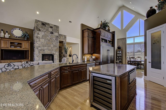 kitchen featuring beverage cooler, appliances with stainless steel finishes, a sink, and light wood-style flooring