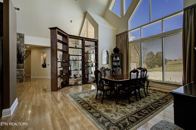 dining space featuring plenty of natural light, a high ceiling, visible vents, and hardwood / wood-style floors