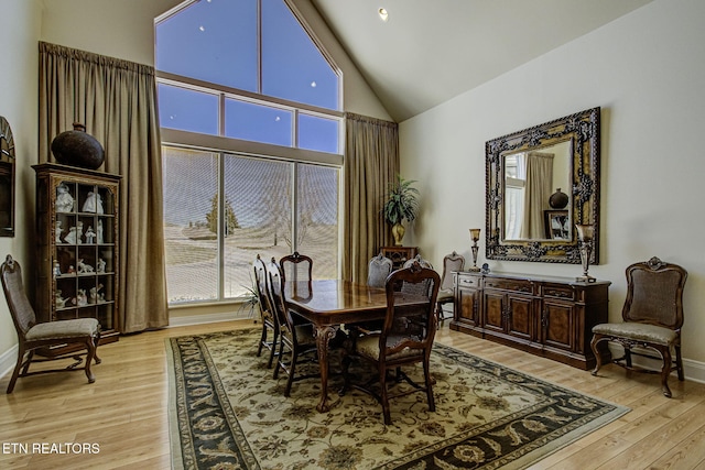 dining area featuring high vaulted ceiling, light wood finished floors, and a wealth of natural light