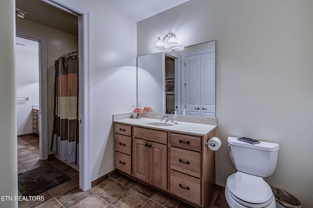 bathroom with toilet, vanity, and baseboards