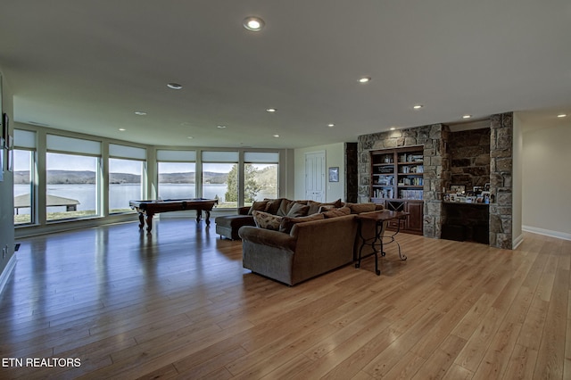 living area with light wood finished floors, billiards, baseboards, a water view, and recessed lighting