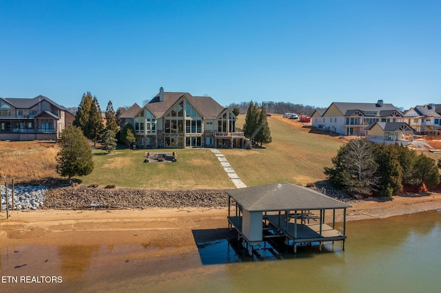 view of dock with a water view, boat lift, and a yard