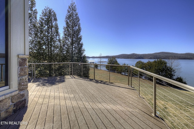 wooden terrace with a yard and a water view