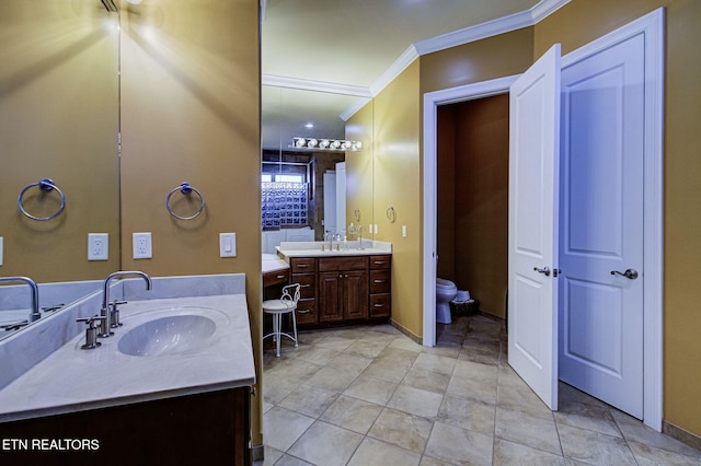 full bathroom with ornamental molding, two vanities, a sink, and toilet