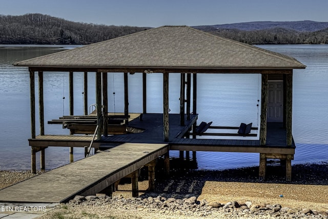 view of dock with boat lift, a view of trees, and a water and mountain view