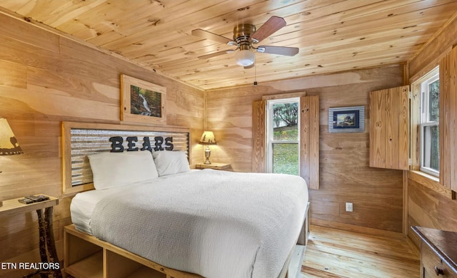 bedroom with ceiling fan, wooden walls, light hardwood / wood-style floors, and wooden ceiling