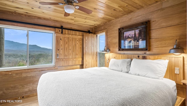 bedroom with wood walls, hardwood / wood-style flooring, ceiling fan, wood ceiling, and a mountain view