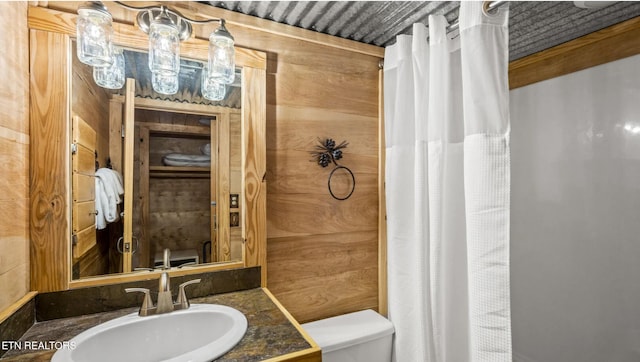 bathroom with vanity, wood walls, and toilet