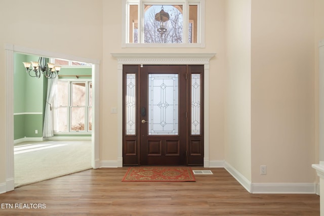 foyer entrance featuring a high ceiling, an inviting chandelier, and light hardwood / wood-style floors