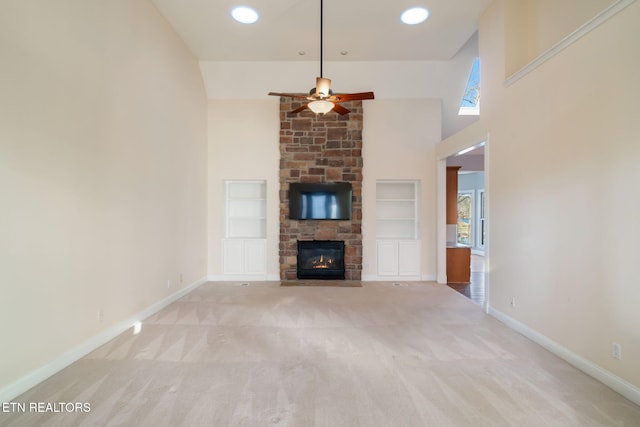 unfurnished living room with ceiling fan, a fireplace, light carpet, and built in features