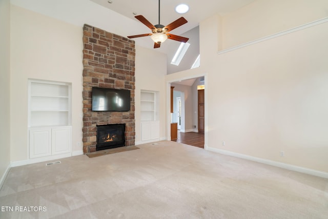 unfurnished living room with high vaulted ceiling, carpet floors, built in features, and a fireplace