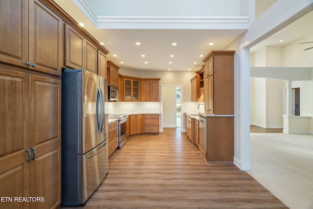 kitchen with stainless steel appliances, light wood-type flooring, and decorative columns