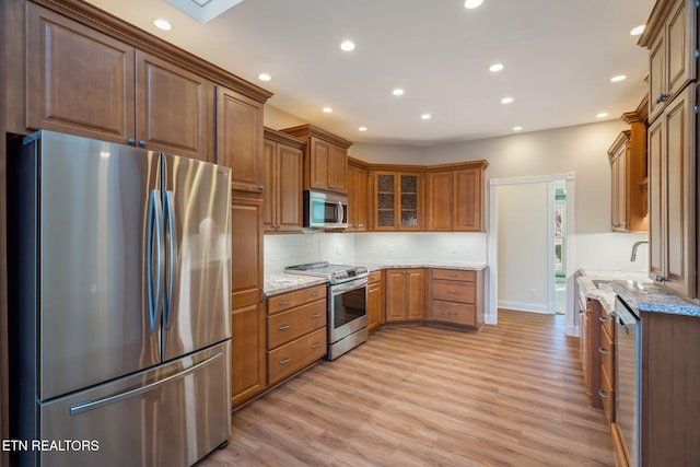 kitchen featuring light stone countertops, stainless steel appliances, sink, and light wood-type flooring