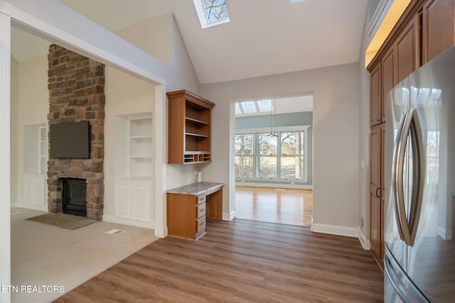 kitchen featuring hardwood / wood-style floors, stainless steel fridge, a fireplace, and a skylight