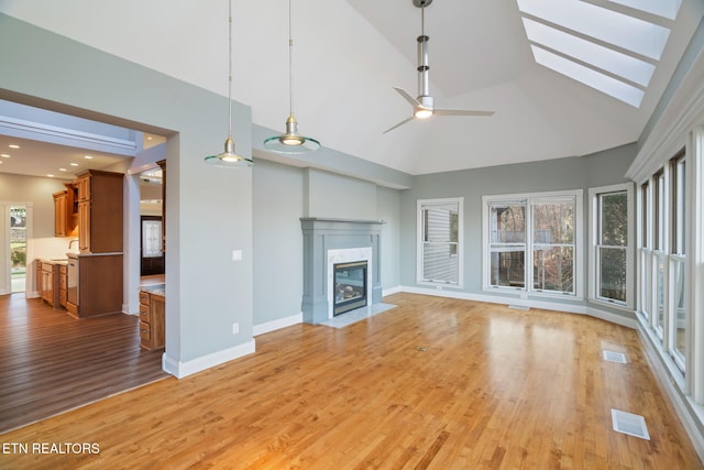 unfurnished living room featuring ceiling fan, a high end fireplace, high vaulted ceiling, and light hardwood / wood-style flooring