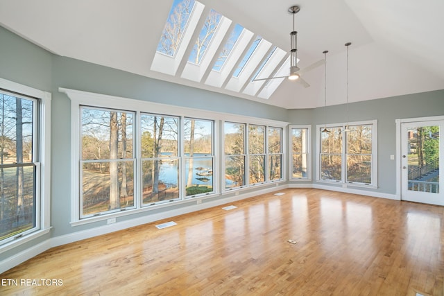 unfurnished sunroom with a wealth of natural light, lofted ceiling with skylight, ceiling fan, and a water view