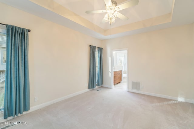 carpeted spare room featuring ceiling fan and a tray ceiling