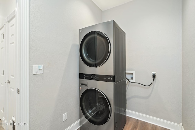 clothes washing area featuring dark hardwood / wood-style flooring and stacked washer / dryer