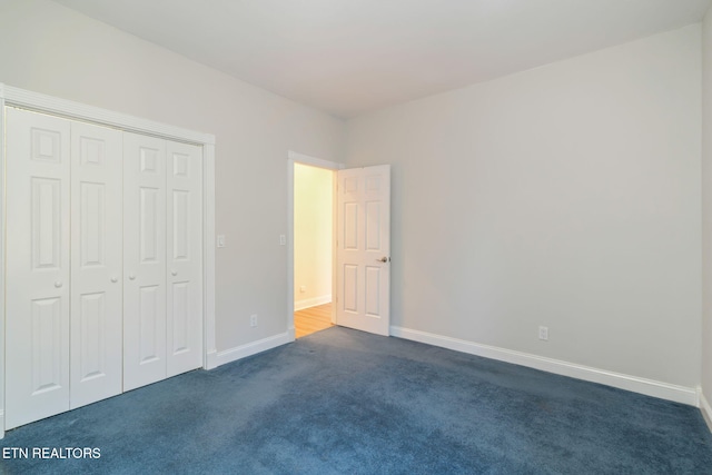 unfurnished bedroom with a closet and dark colored carpet