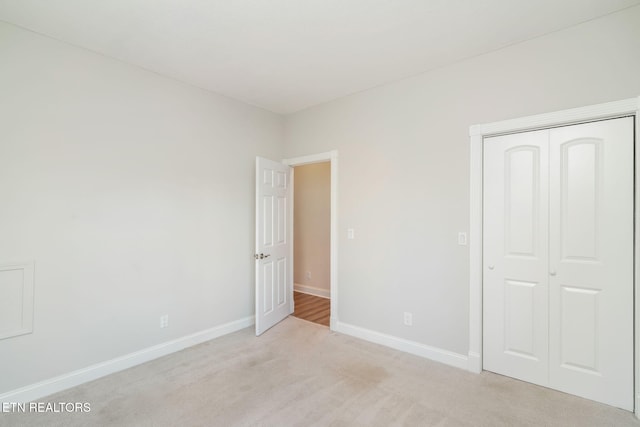 unfurnished bedroom featuring light carpet and a closet