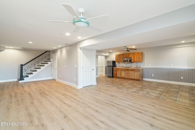 unfurnished living room featuring sink, light hardwood / wood-style flooring, and ceiling fan