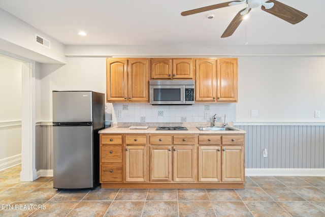 kitchen with stainless steel appliances, sink, ceiling fan, and decorative backsplash