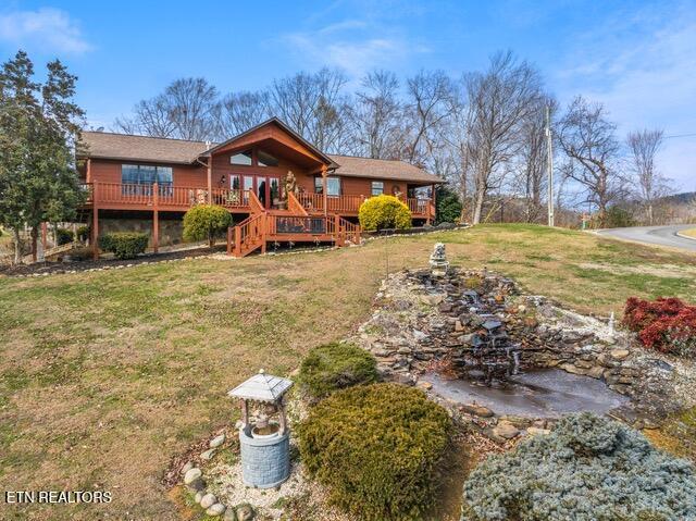 rear view of house featuring a wooden deck and a lawn