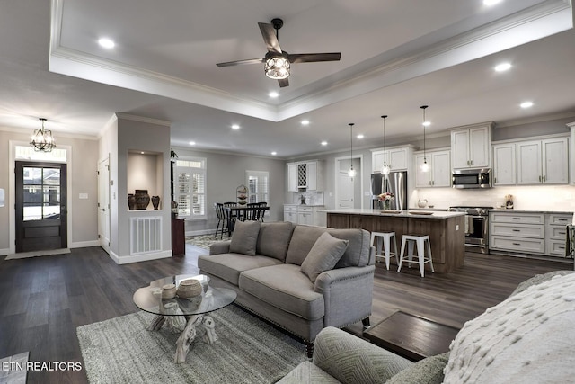 living room featuring a raised ceiling, ornamental molding, a healthy amount of sunlight, and dark hardwood / wood-style flooring