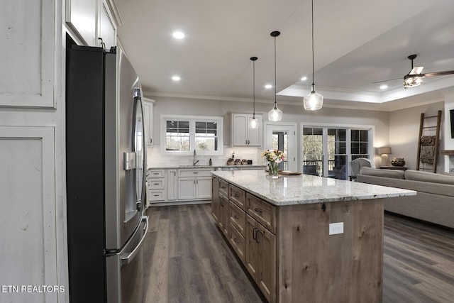 kitchen with dark hardwood / wood-style floors, white cabinets, stainless steel fridge, hanging light fixtures, and a center island