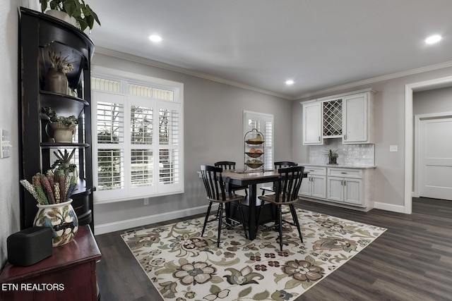 dining space with dark hardwood / wood-style flooring, ornamental molding, and bar area