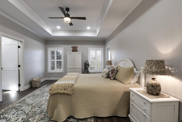 bedroom with crown molding, dark hardwood / wood-style floors, ceiling fan, and a tray ceiling