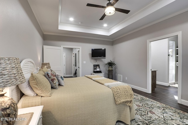 bedroom with dark hardwood / wood-style flooring, a tray ceiling, crown molding, and ceiling fan