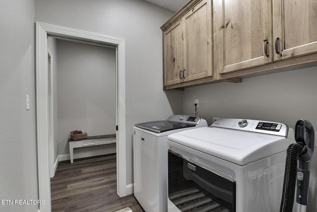 laundry room featuring dark wood-type flooring, washer and clothes dryer, and cabinets